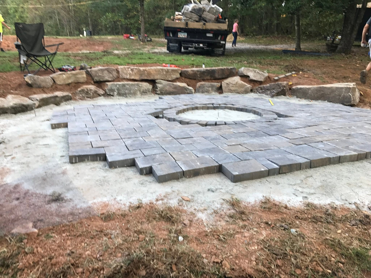 Fire pit paver patio framed by a natural boulder wall